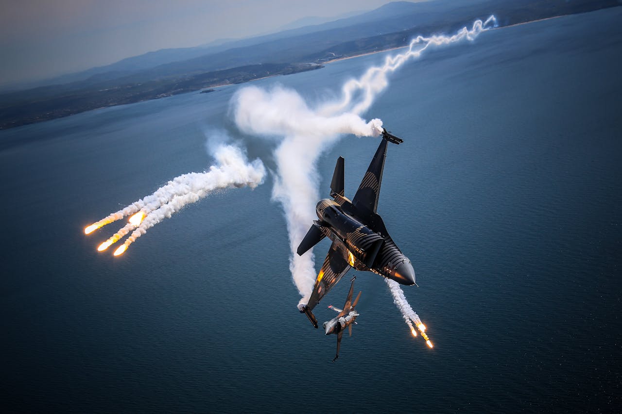 Fighter jet performing an aerial maneuver with smoke trails over the ocean, displaying agility and power.